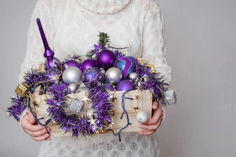 female holding box full purple ornaments
